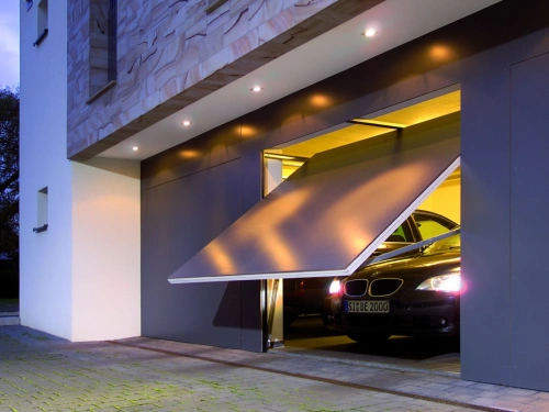 Porte de garage basculante anthracite AFC entrouverte de nuit, villa contemporaine à Caen.