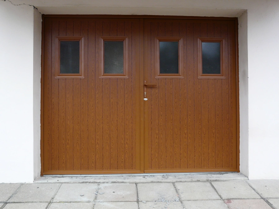 Porte de garage battante chêne doré AFC à hublots, façade crépi blanc dans le Calvados.