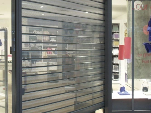 Rideau métallique micro-perforé anthracite AFC sur devanture de boutique à Caen.