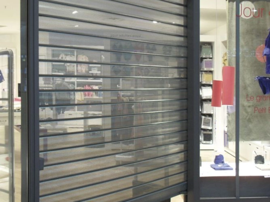 Rideau métallique micro-perforé anthracite AFC sur devanture de boutique à Caen.