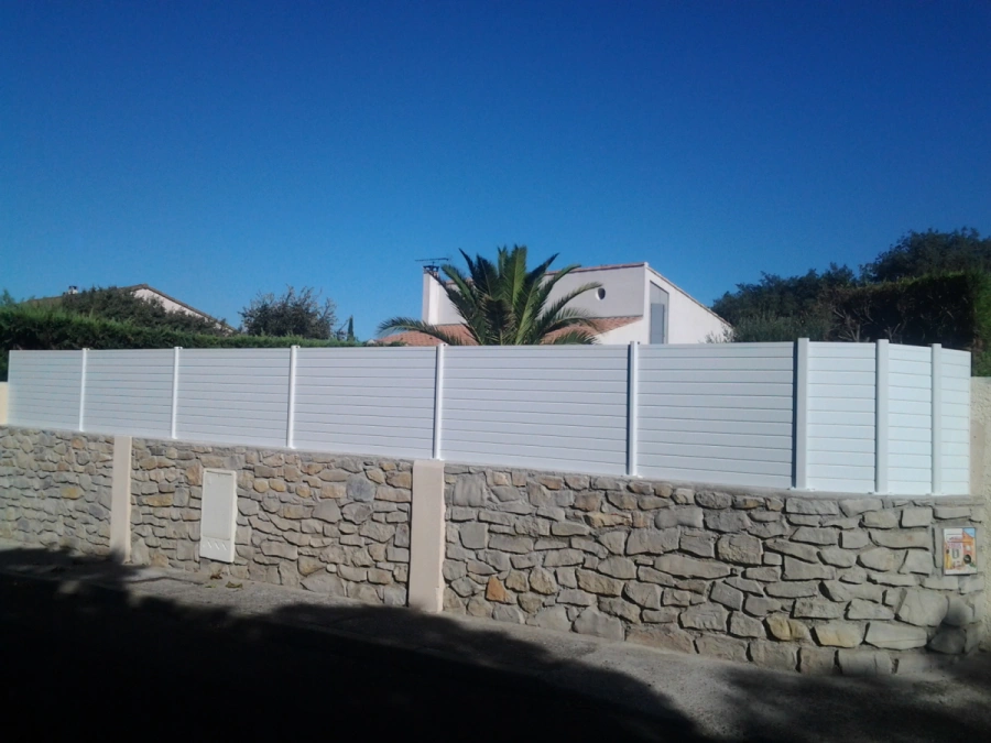 Claustra blanc à lames horizontales AFC sur muret pierre, intimité jardin en Calvados.