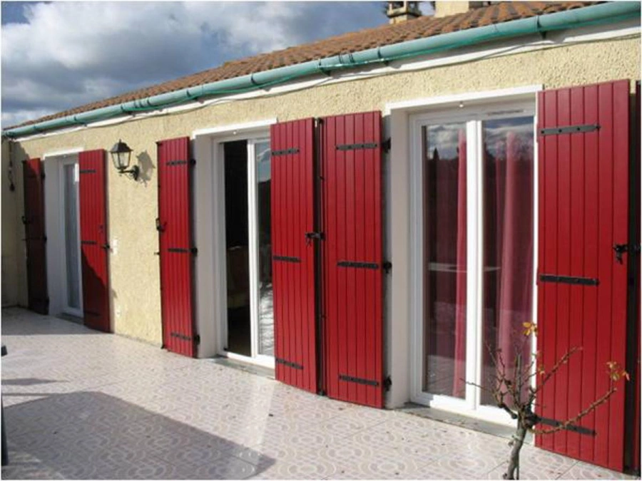 Volets battants rouge profond AFC à lames verticales sur façade beige, maison Calvados.