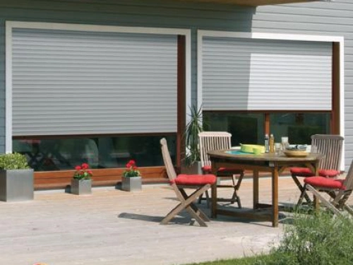 Volets roulants gris clair AFC sur baies bois, terrasse repas ensoleillée Calvados.