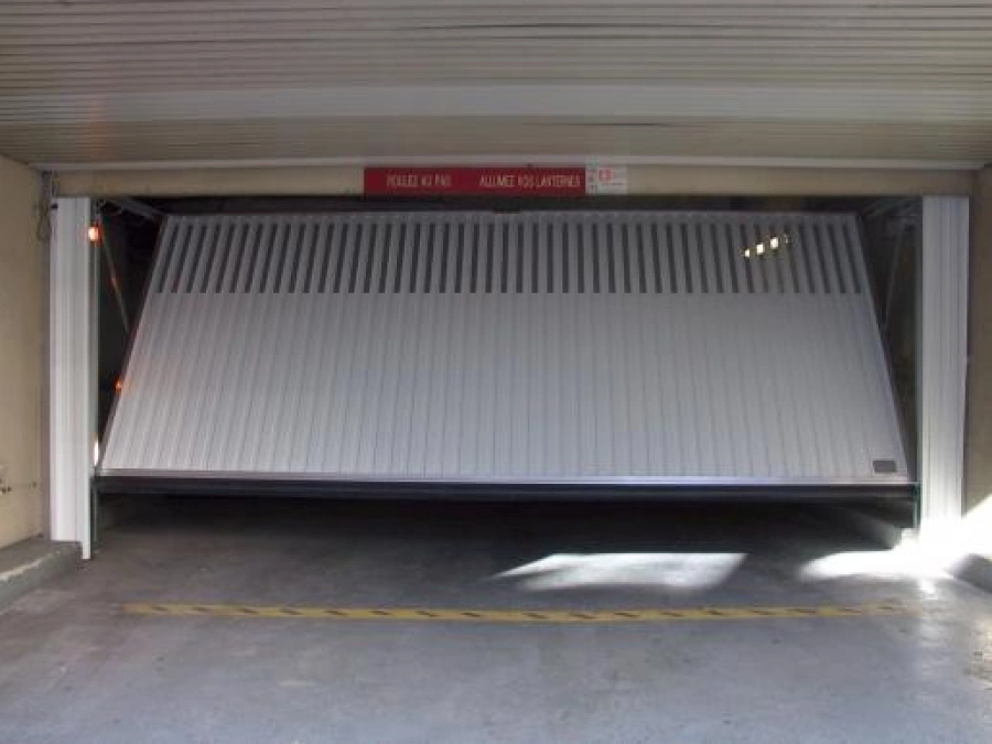 Porte collective basculante blanche AFC ventilée, accès parking souterrain à Caen.