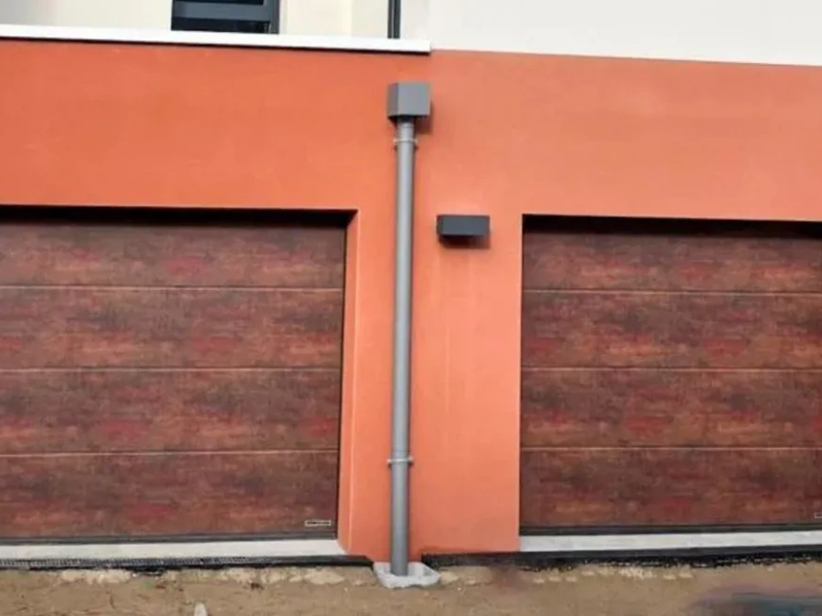 Deux portes sectionnelles Hormann à effet rouille type Corten sur façade terracotta, maison neuve AFC Calvados.