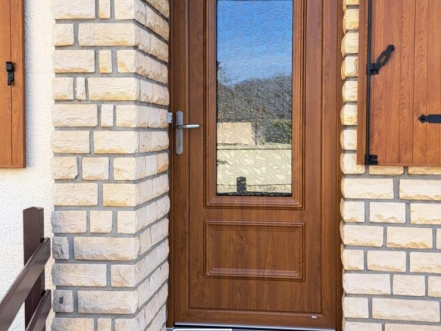 Porte d'entrée aspect bois avec oculus vitré cintré et volets assortis, façade pierre près de Caen