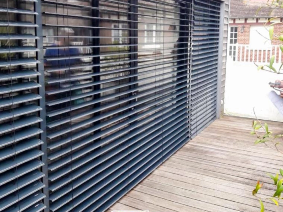 Brise-soleil à lames orientables anthracite sur maison à bardage bois, protection solaire AFC Caen