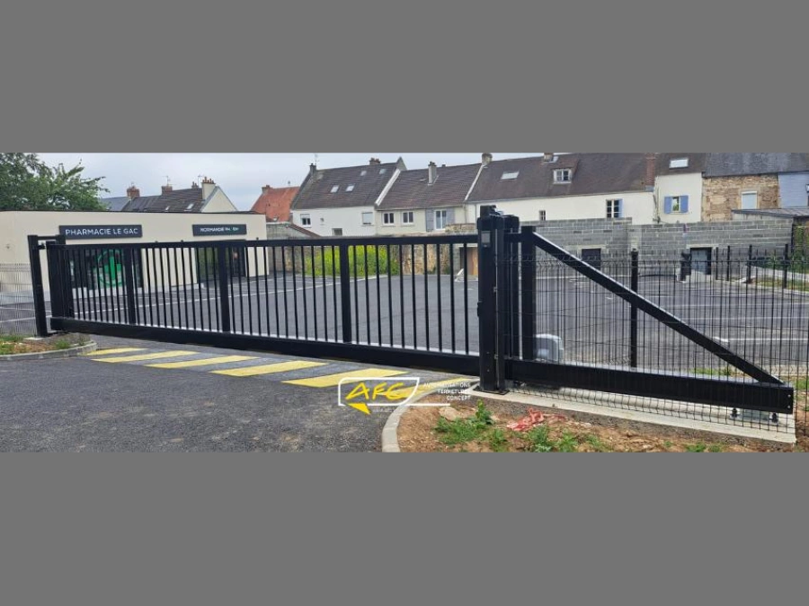 Portail coulissant autoportant noir motorisé devant une pharmacie, accès parking professionnel installé par AFC à Caen.