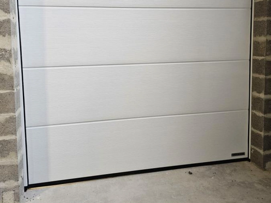 Porte sectionnelle Hormann blanche vue de l'intérieur d'un garage en construction, pose AFC dans le Calvados.