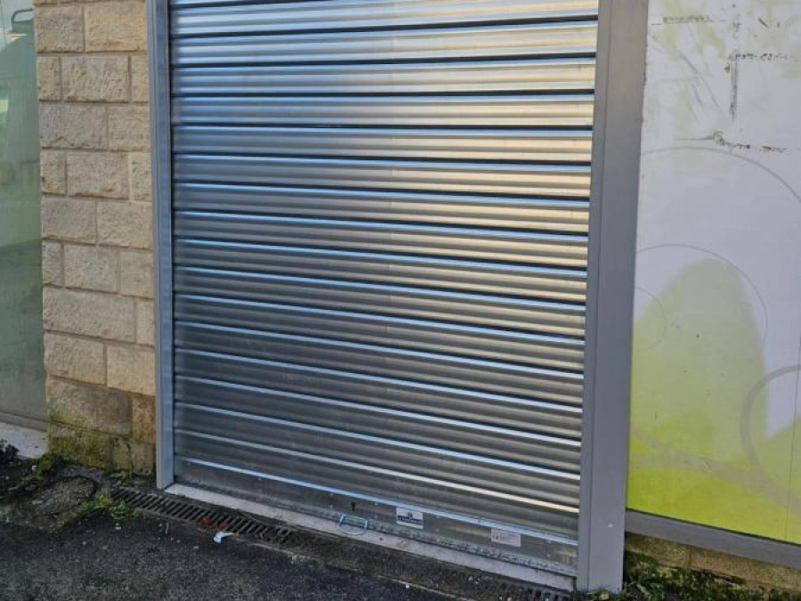 Façade de pharmacie rénovée avec rideau métallique argenté et châssis anthracite, réhabilitation AFC à Caen.