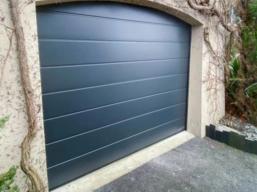 Porte de garage sectionnelle Hormann anthracite sous arche maçonnée, façade avec glycine, réalisation AFC Caen.