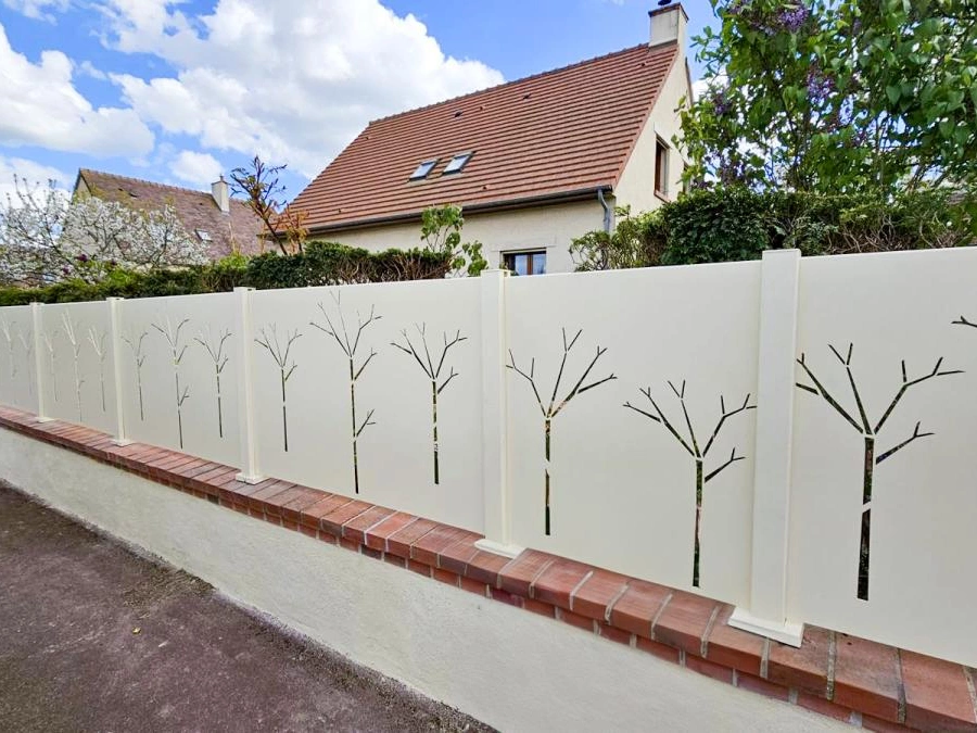 Clôture aluminium ivoire à découpe laser motif arbres sur muret de briques, façade résidentielle AFC Calvados.