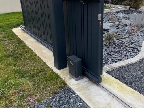 Portail coulissant aluminium anthracite motorisé DEA, vue depuis le jardin au coucher du soleil, AFC Caen