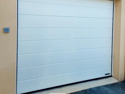 Vue de face d'une porte de garage Hormann blanche motorisée sur crépi beige, réalisation AFC Calvados.