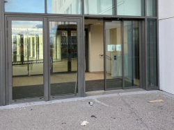 Entrée de bâtiment avec porte automatique coulissante et châssis aluminium anthracite, réalisation AFC près de Caen.