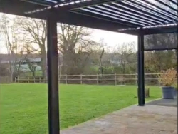 Pergola bioclimatique à lames orientables et éclairage LED intégré, store latéral, terrasse pavée AFC près de Caen.