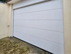 Porte de garage sectionnelle blanche Hormann Renomatic sous toiture ardoise, maison près de Caen, AFC.