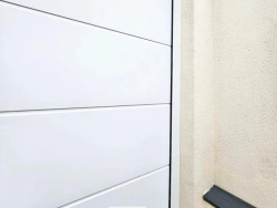 Détail en angle d'une porte de garage Hormann Renomatic blanche sur crépi beige, pose AFC Calvados.