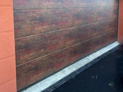 Porte de garage sectionnelle Hormann effet métal rouillé sur crépi orange, allée asphaltée, pose AFC près de Caen.