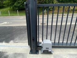Gros plan moteur DEA sur portail coulissant acier anthracite, rail au sol, installation AFC