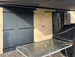Store banne anthracite à coffre déployé sur façade, terrasse et volets assortis, AFC Calvados