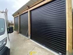 Trois portes enroulables noires sur structure bois, rideaux métalliques garage bateaux AFC