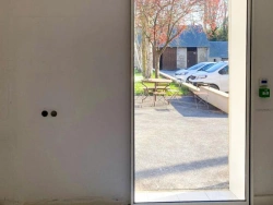 Porte coulissante automatique blanche ouverte sur cour, capteur et bouton secours, AFC Caen