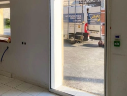 Porte automatique vitrée ouverte, fourgon AFC visible dans la cour, pose Calvados
