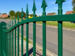 Détail des fleurons en fer de lance d'un portail Ferplay vert, ciel bleu, AFC Calvados