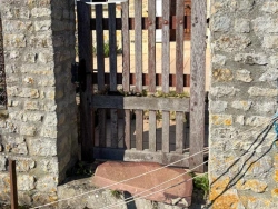 Ancien portillon bois ajouré entre piliers de pierre, maison normande en fond, avant remplacement près de Caen
