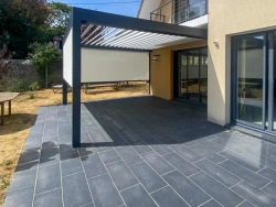 Pergola bioclimatique alu gris avec store ZIP latéral et lames orientables, terrasse carrelée en Calvados