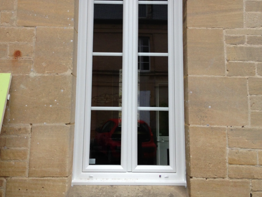 Fenêtre PVC blanche cintrée à petits bois sur façade en pierre de Caen, pose AFC