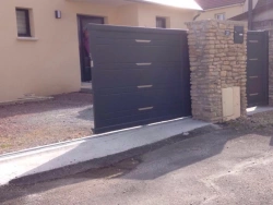 Portail coulissant aluminium gris anthracite entrouvert avec portillon, entrée résidentielle dans le Calvados