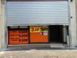 Rideau métallique argenté mi-ouvert sur vitrine de commerce, installation AFC dans le Calvados