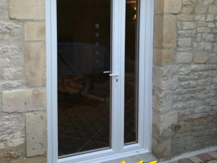Porte-fenêtre blanche vitrée avec stores intégrés dans mur en pierre, rénovation AFC Calvados