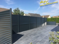 Claustra aluminium gris occultant sur terrasse dallée, intimité jardin en Normandie, pose AFC