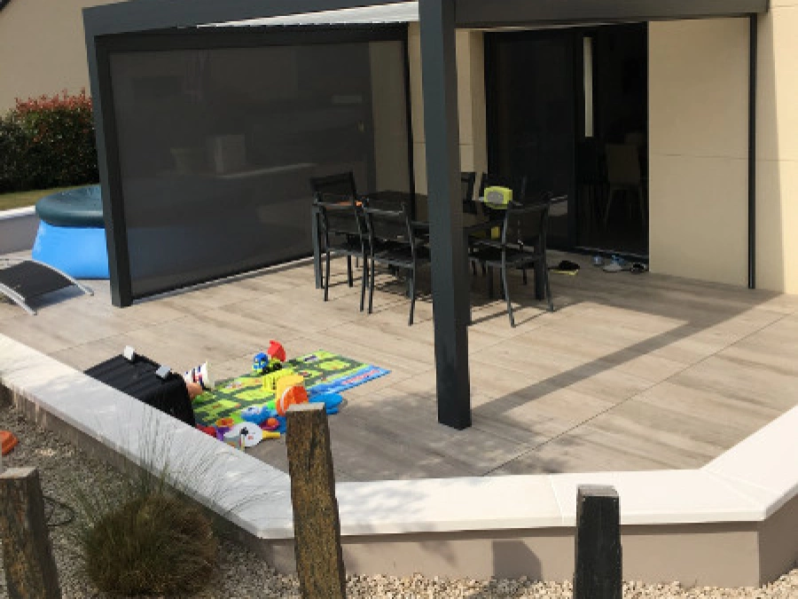 Pergola bioclimatique anthracite avec store latéral sur terrasse de maison près de Caen, réalisation AFC