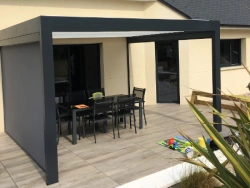 Pergola aluminium gris anthracite et lames blanches sur terrasse carrelée, jardin résidentiel Calvados