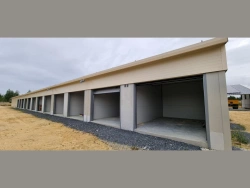 Façade de box avec portes de garage sectionnelles grises pour locaux professionnels en Normandie