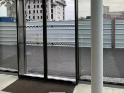 Vue intérieure d'une porte coulissante automatique vitrée cadre noir, bâtiment tertiaire Calvados